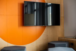 Telewizor na tle pomarańczowej ściany, dodającej energii i koloru do wnętrza.