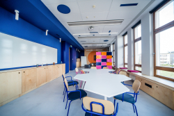 Klasa o niebieskich ścianach i krzesłach, idealna do zajęć edukacyjnych i twórczych dyskusji.