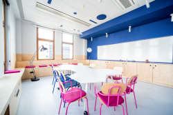 Wnętrze klasy z niebieskimi ścianami i krzesłami, sprzyjające nauce i współpracy uczniów.