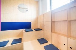 Przestrzeń z drewnianymi ławkami i niebieską ścianą, idealna do kreatywnej współpracy.