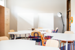 Biały stół otoczony krzesłami w przestrzeni sprzyjającej kreatywnej współpracy.