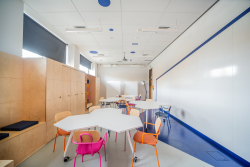 Wnętrze przestrzeni kreatywnej z stołami i krzesłami, sprzyjające współpracy i twórczym spotkaniom.