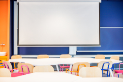 Biały ekran zamontowany na ścianie, idealny do prezentacji lub wyświetlania multimediów.