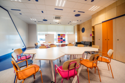 Klasa z kolorowymi krzesłami i stołami, stwarzająca przyjazną atmosferę do nauki i współpracy