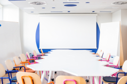 Długi, biały stół z krzesłami, idealny do wspólnej pracy i spotkań w przyjemnej atmosferze.