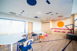 Jasny pokój z kolorowymi meblami, stworzony z myślą o współpracy i inspirujących rozmowach.