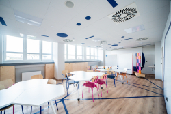 Klasa z ustawionymi stołami i krzesłami, sprzyjająca współpracy i nauce w przyjaznej atmosferze.