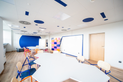 Klasa z niebieskimi i białymi krzesłami oraz stołami, stworzona z myślą o współpracy.