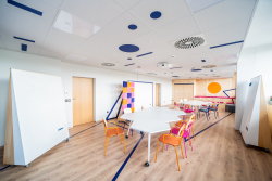 Pokój z białym stołem i krzesłami, idealny do spotkań i współpracy w przyjemnej atmosferze.